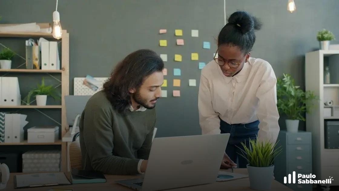 Homem e mulher observam notebook juntos em escritório com post-its coloridos na parede