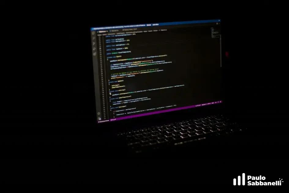 Silhueta escura de um notebook aberto com tela de código ao fundo