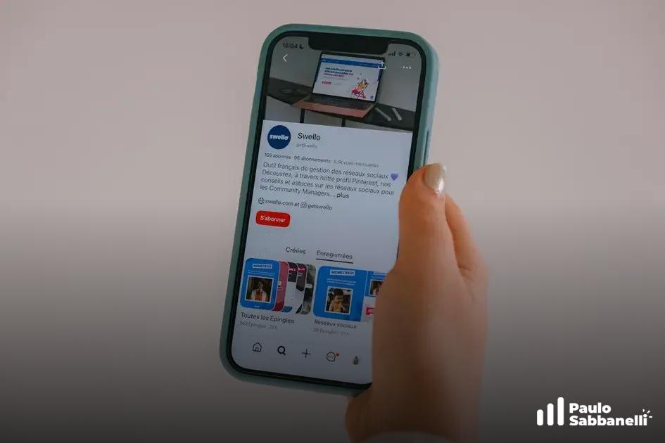Mão segurando smartphone verde-água com publicação da Swello na tela