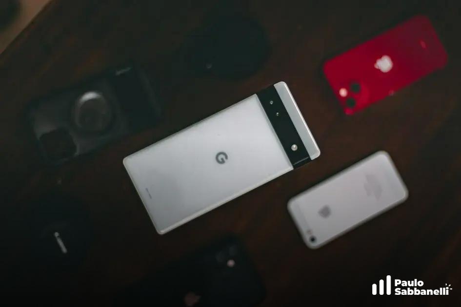 Smartphones dispostos sobre mesa escura, um deles com o logotipo do Google na tela