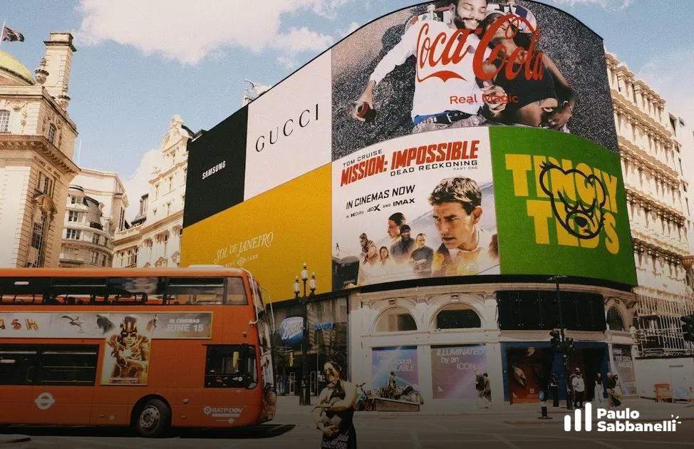 Painéis publicitários digitais de grandes marcas em cruzamento movimentado com ônibus de dois andares