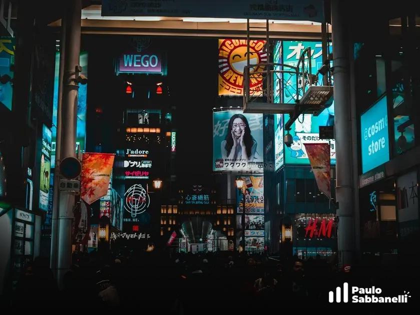 Rua movimentada à noite com painéis luminosos coloridos de propaganda em cidade asiática