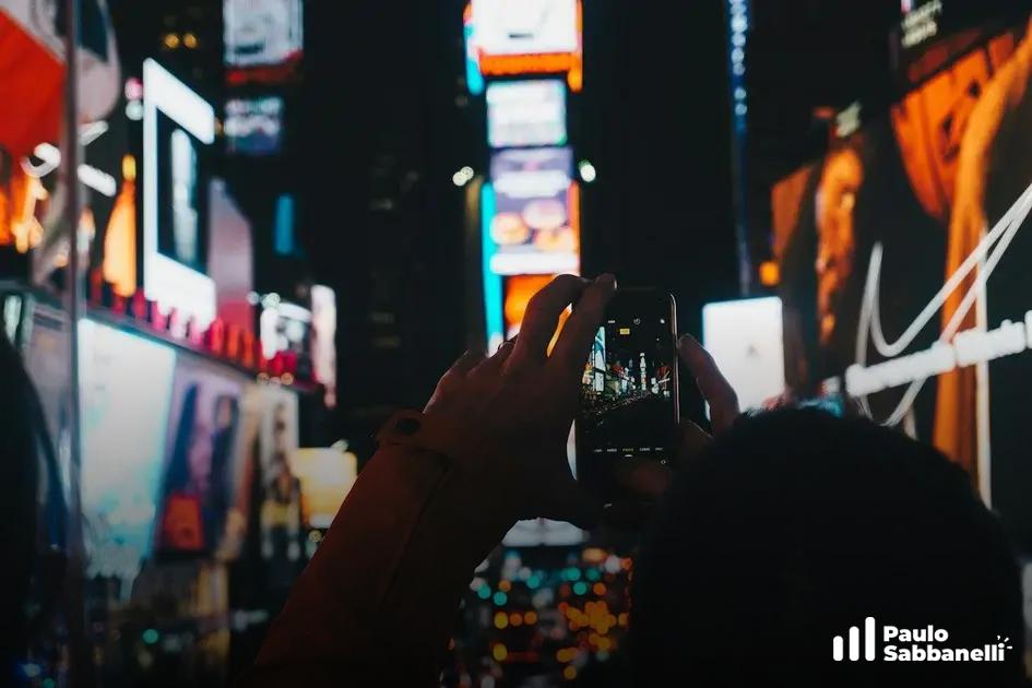 Pessoa fotografa painéis publicitários iluminados da Times Square com o celular
