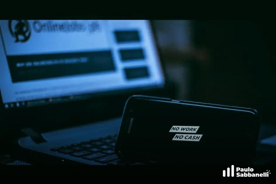 Celular com adesivo No Work No Cash apoiado sobre o teclado de um notebook com site de empregos