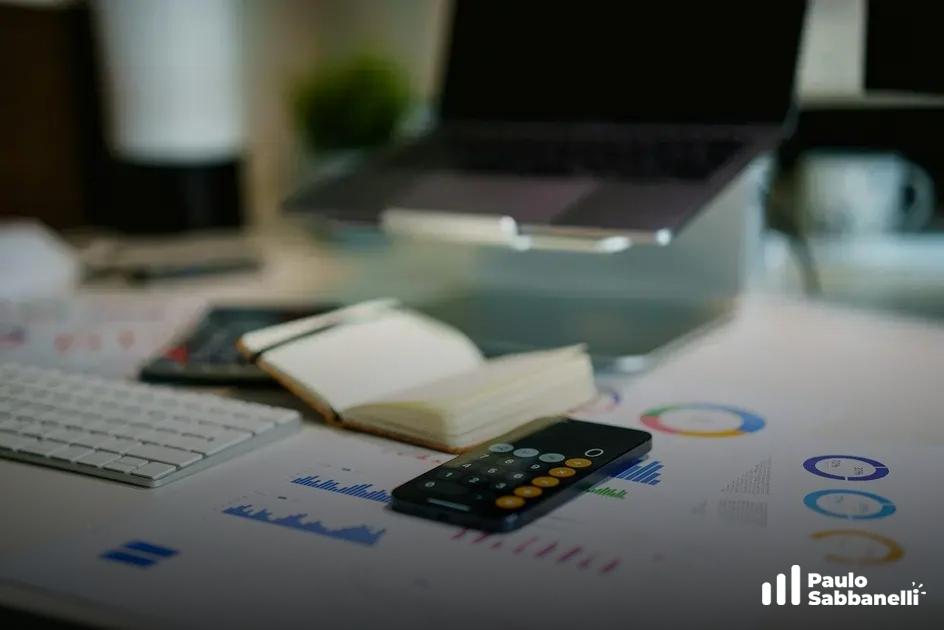 Mesa de trabalho com notebook, calculadora e relatório impresso com gráficos de barras