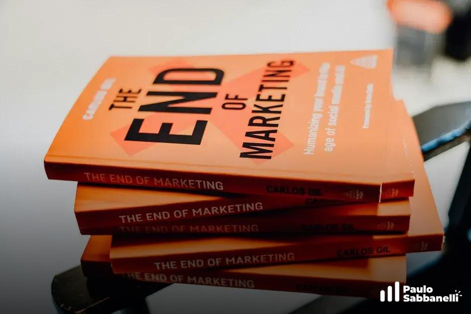 Pilha de exemplares do livro The End of Marketing, de capa laranja, sobre mesa escura