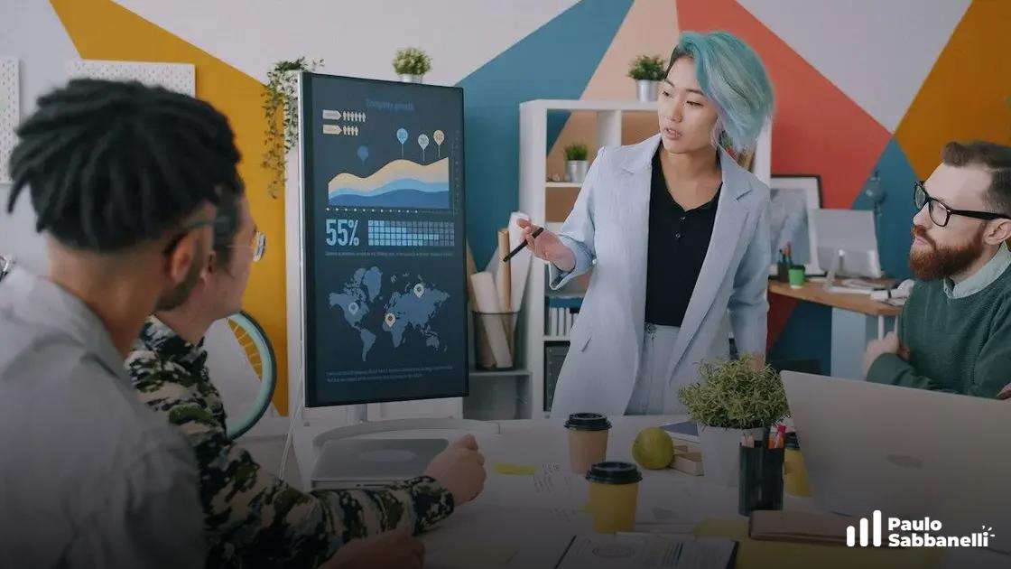 Mulher apresenta gráficos e mapa em tela para colegas reunidos à mesa colorida