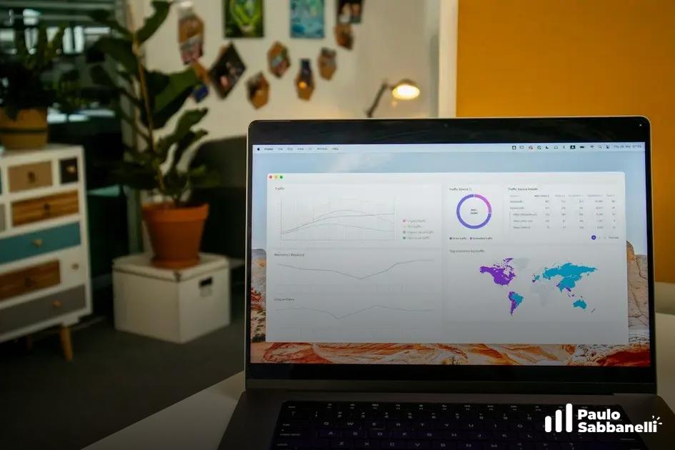 Notebook aberto mostra painel com mapa múndi e gráficos, ao lado de planta em vaso