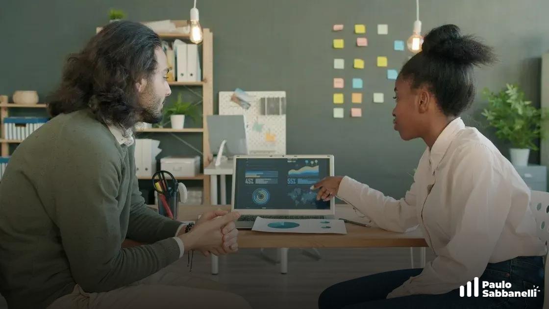 Dois colegas analisam gráficos em laptop durante reunião em escritório com post-its coloridos