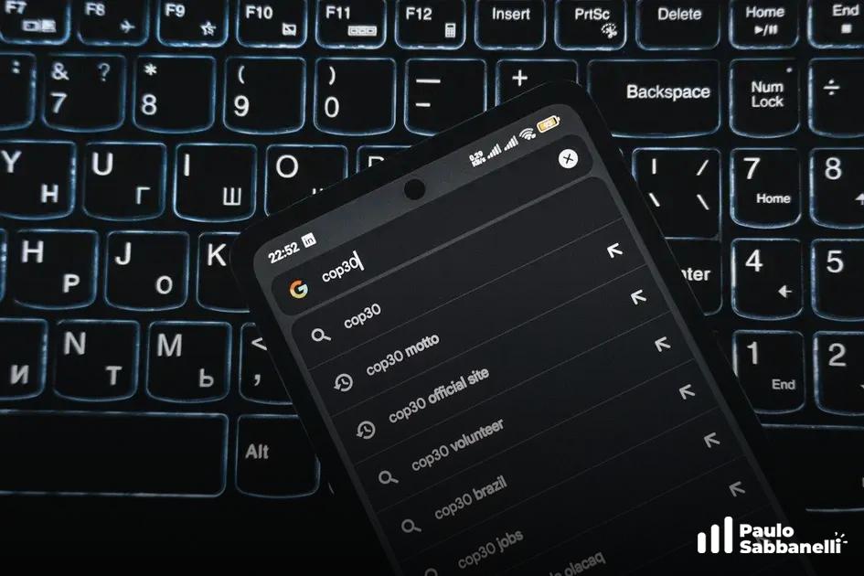 Celular apoiado em teclado retroiluminado exibindo sugestões de busca para cop30 no Google