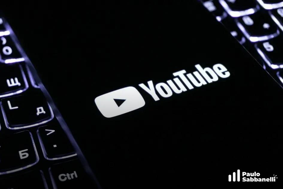 Tela de celular exibindo o logotipo do YouTube sobre fundo preto com teclado ao lado